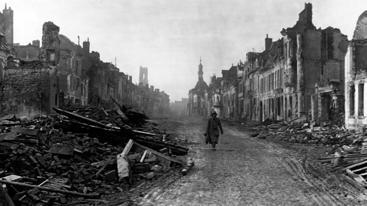 A german soldier walking through the ruins of Peronne.