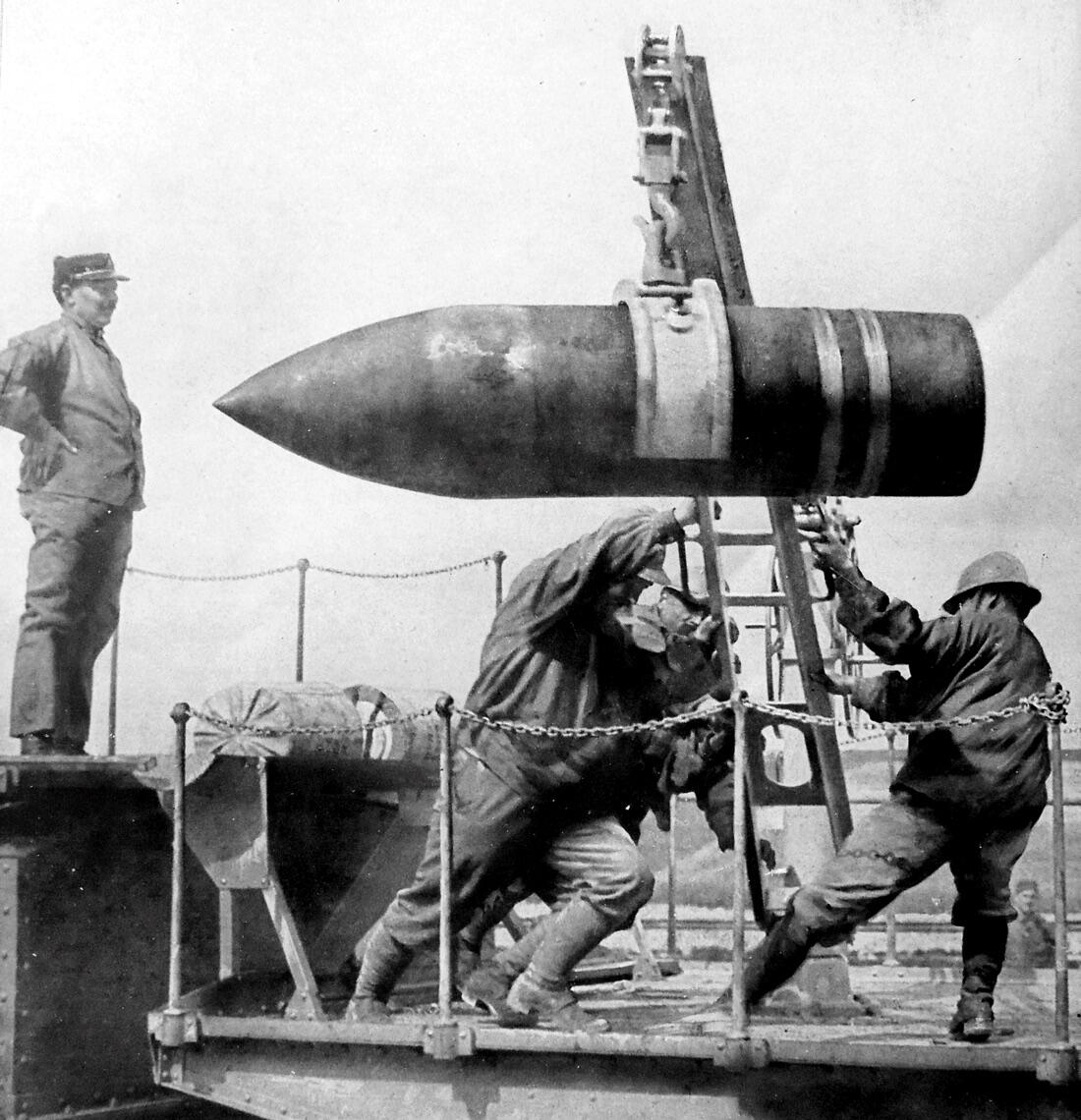 An artillery shell is hoisted into position by soldiers.