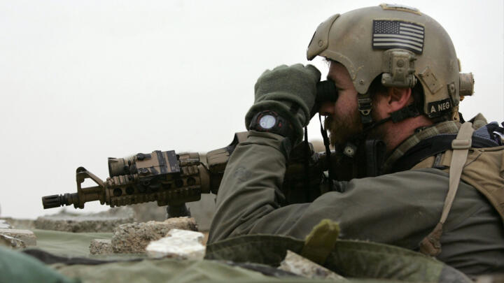 A U.S. Navy Seal looks towards insurgent movements from the rooftop of an observation post.