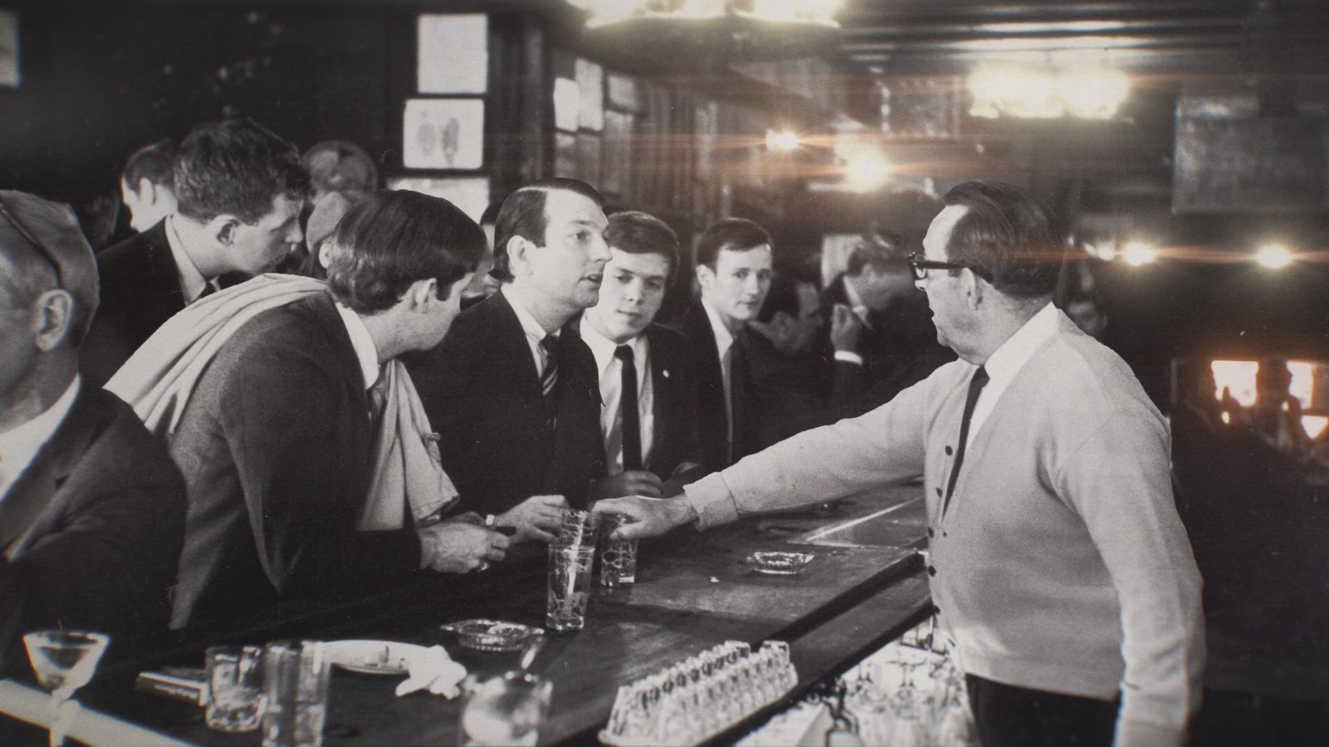 a photo of men at a bar, looking at the bartender