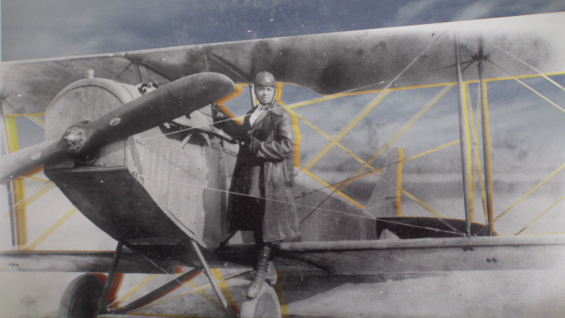 a photo of bessie coleman aka queen bess posing on the wheel of her plane