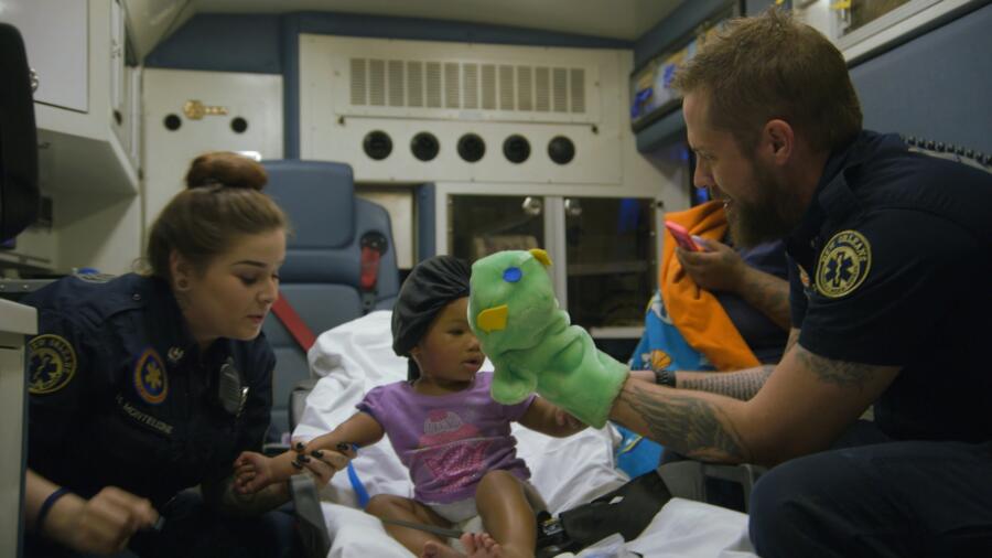 Nick distracts a young patient while Holly starts an IV