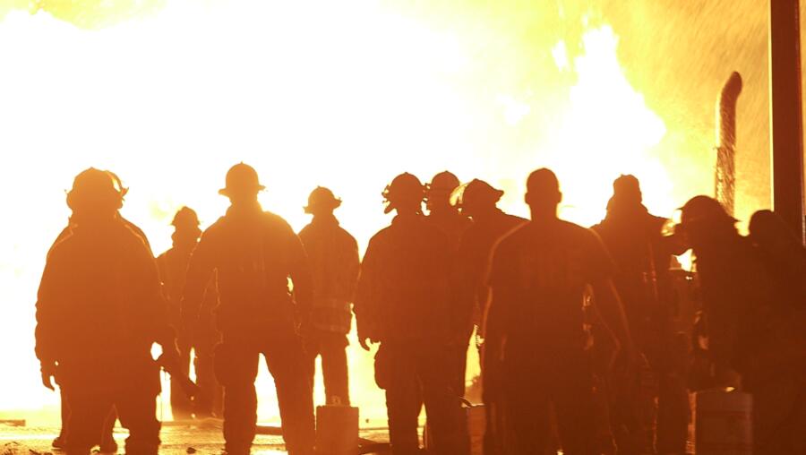 Firefighters watch a fire rage