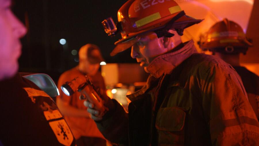 Firefighter examines the engine of a truck after an accident