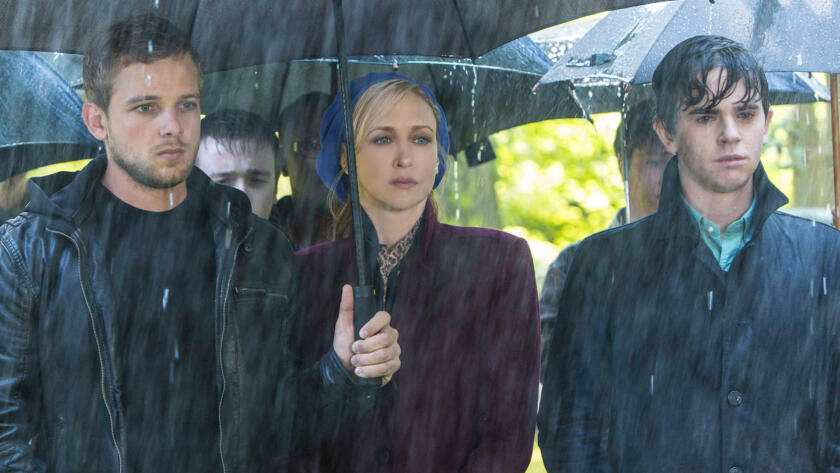 Dylan, Norma, and Norman stand in the rain at Miss Watson's funeral