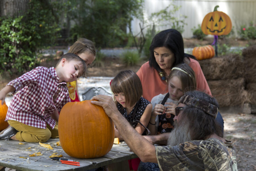 Phil and Kay decorate a jack-o-lantern with their grandkids.