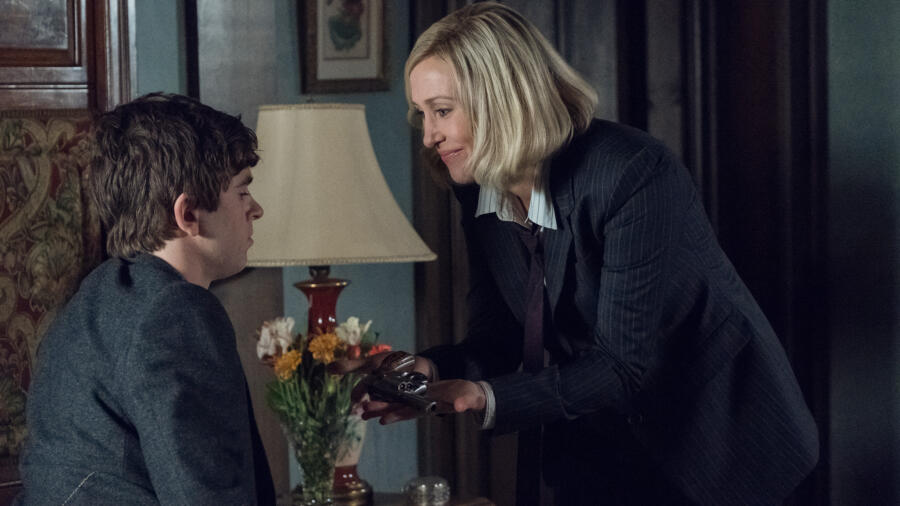 Norma hands Norman a gun.