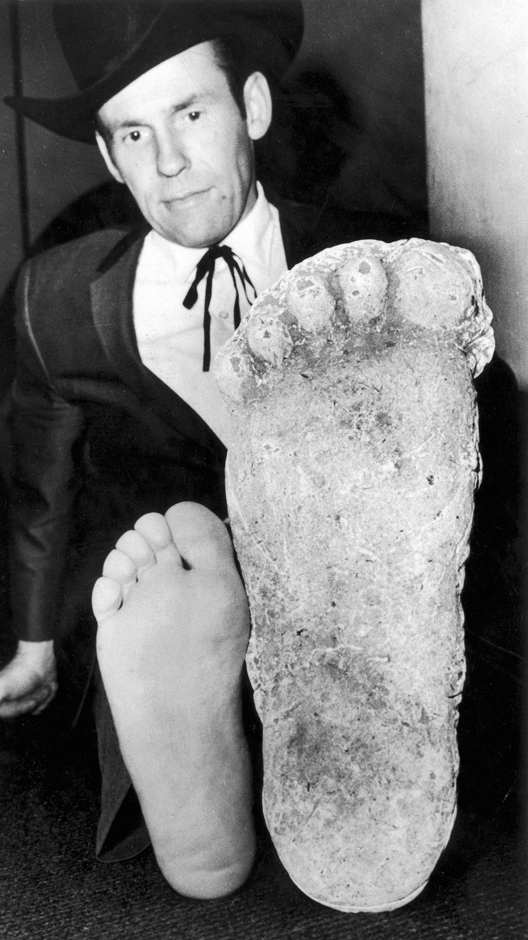 Roger Patterson comparing his foot with a plaster cast of a footprint by the purported 'Bigfoot' or 'Sasquatch'.