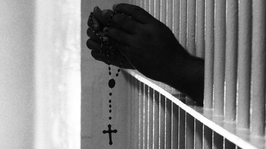 Prison inmate holding a rosary