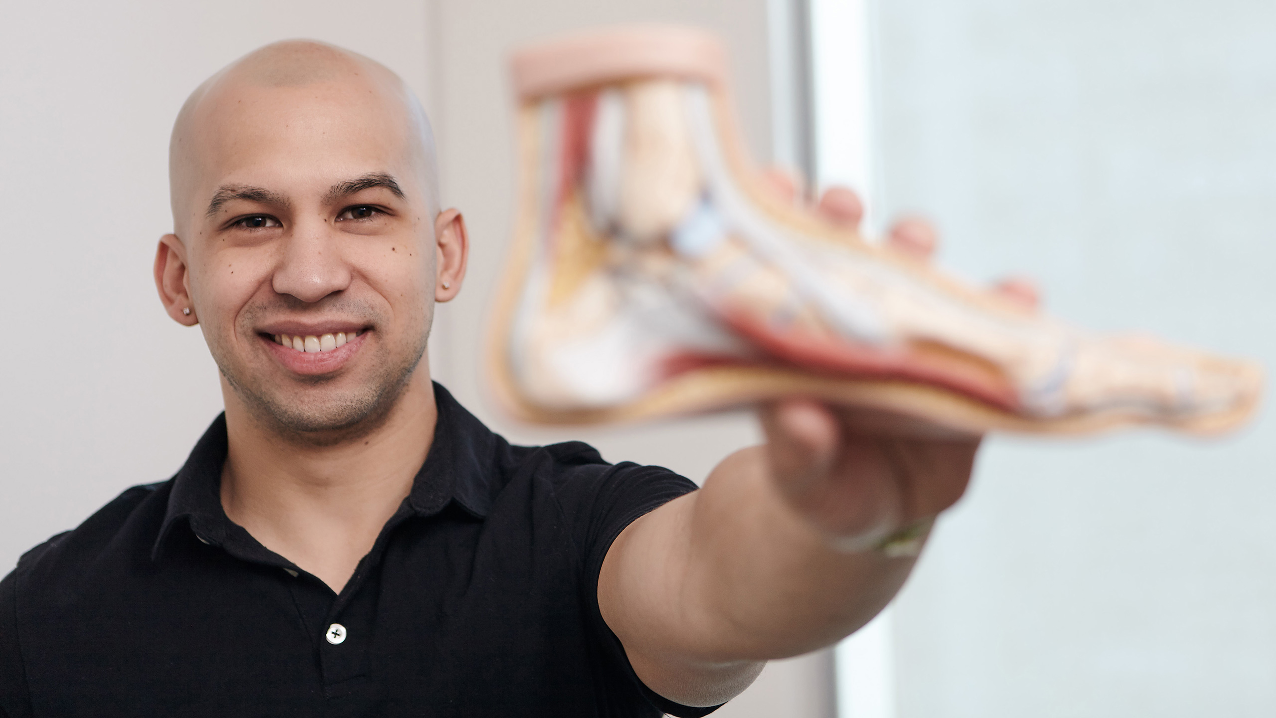Jonathan Tomines holds up a model foot in his office.
