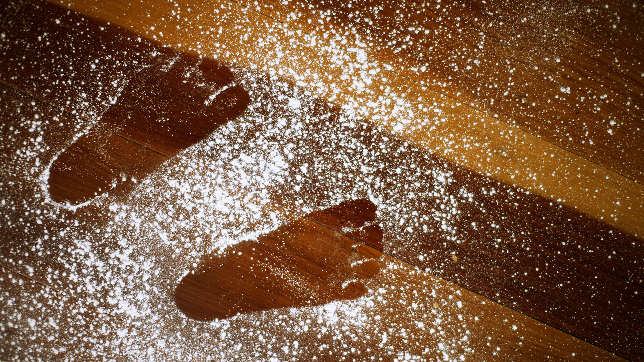 Small footprints left in a pile of talcum powder on a wooden floor