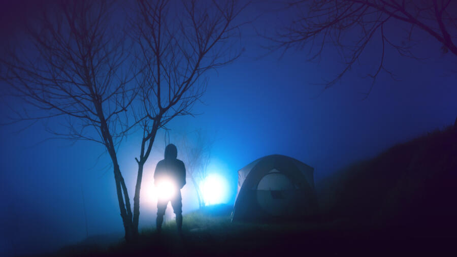 Person standing next to a tent in the dark