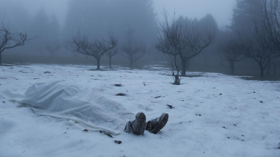 Dead man in the snow covered with a blanket