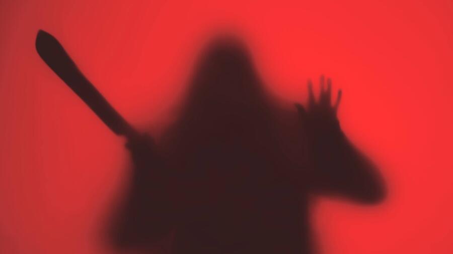 Conceptual image of a silhouette of a person with a machete