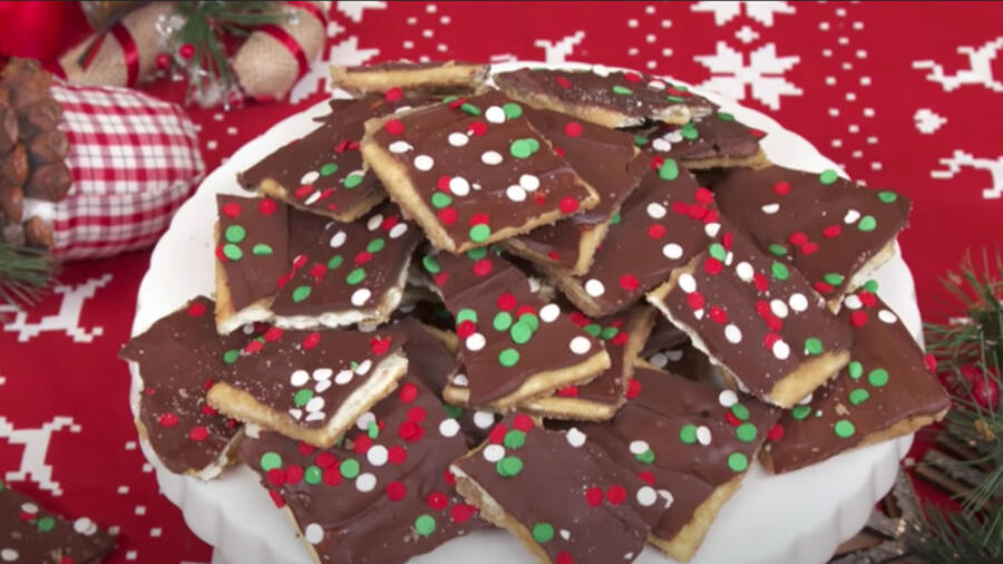 A plate holds a pile of chocolate-frosted and festively-sprinkled square treats.